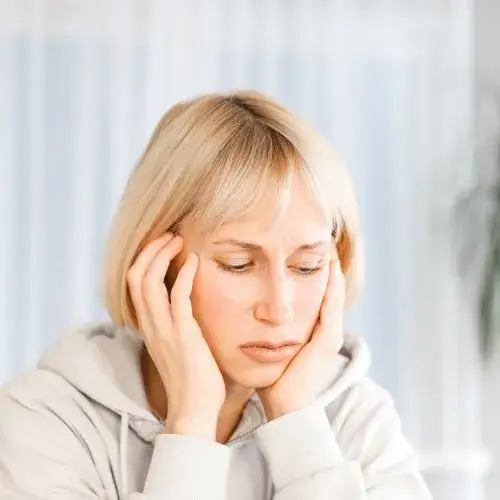 blonde woman wearily resting her chin in her hands